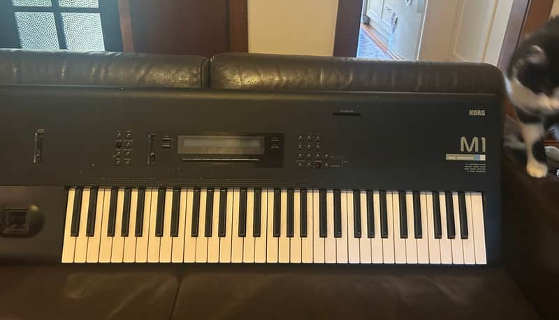 Black keyboard synthesizer with white keys and digital display.