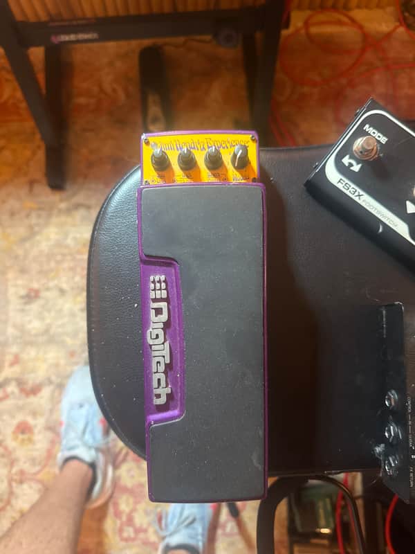 Purple and black guitar effects pedal with gold knobs on wooden surface.