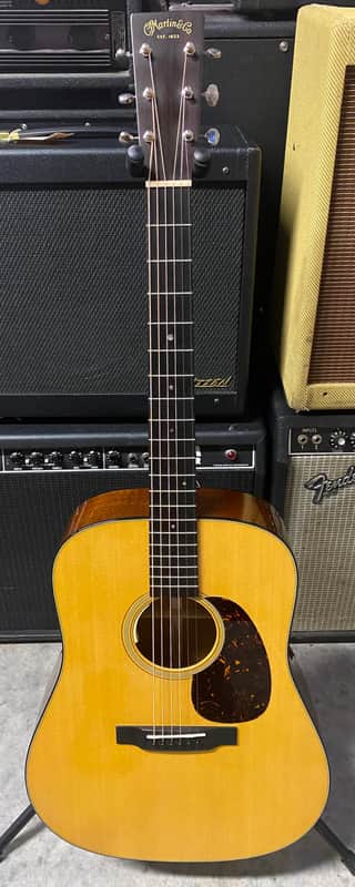 Yellow acoustic guitar on grass, standing upright, natural wood finish.