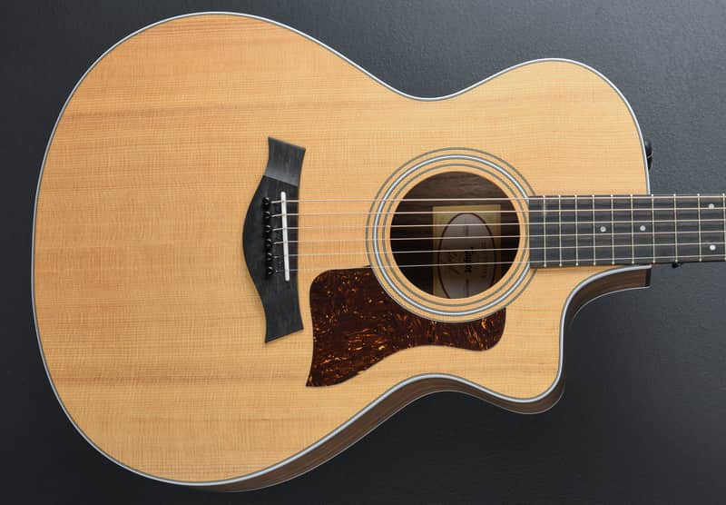 A light wood acoustic guitar with a dark pickguard and soundhole.