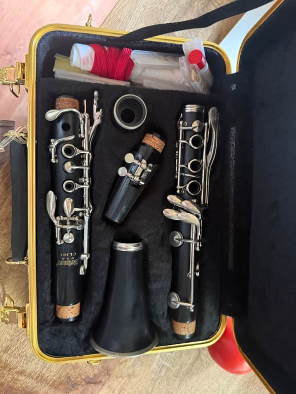 Black and silver saxophone, lying horizontally on a white surface.