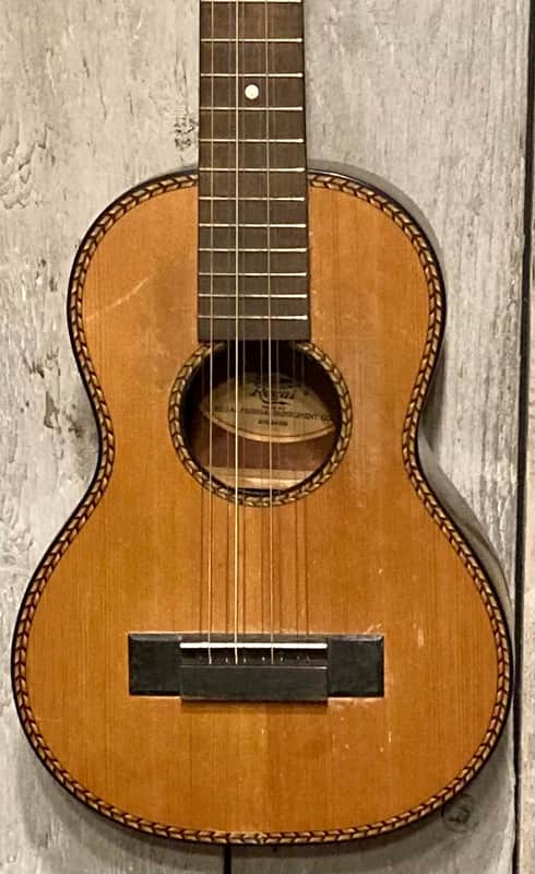 Brown acoustic guitar on wooden table. Natural wood finish, visible strings and tuning pegs.