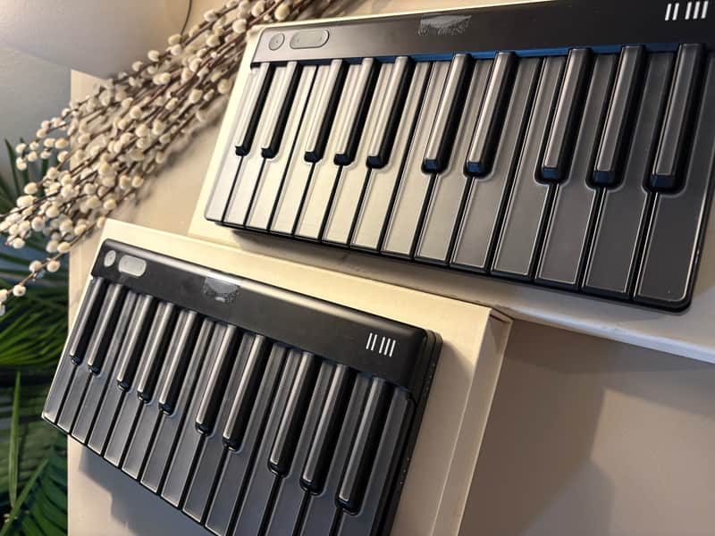 Blue electronic keyboard with white keys, illuminated, resting on a wooden surface.