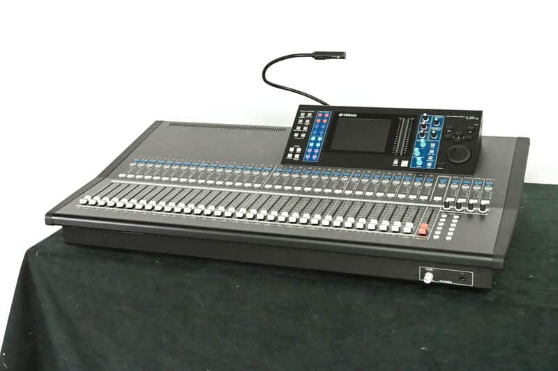 Black audio mixing console with multiple faders and digital display.