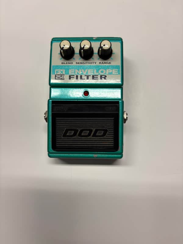 Teal electronic effects pedal with knobs and black input/output jacks.