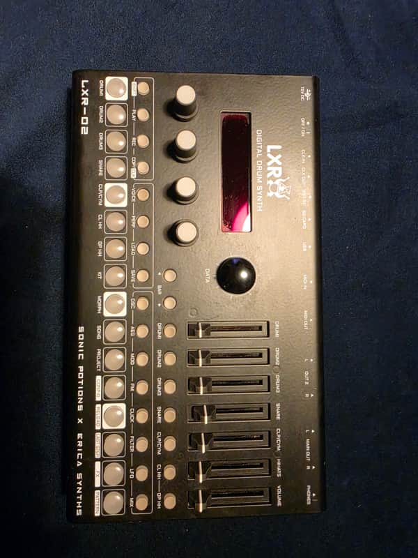 Black digital drum synthesizer with red and white controls. LXR-02 model.