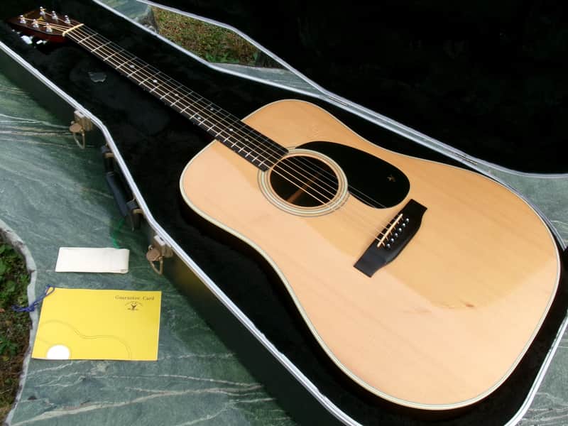 Light brown acoustic guitar in open case, showing soundboard and neck.