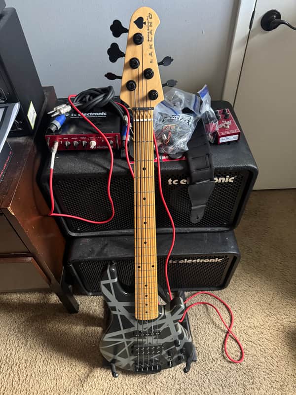 Black electric guitar, standing upright, displayed on a light-colored surface.