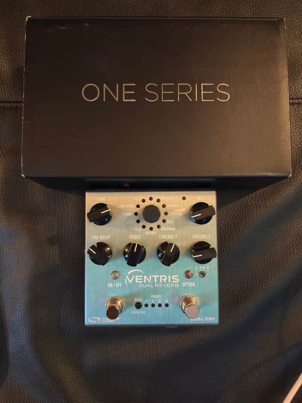 Silver and black guitar effects pedal on a black box.