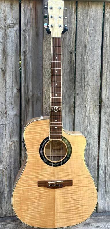 A natural wood acoustic guitar in a black velvet-lined case.
