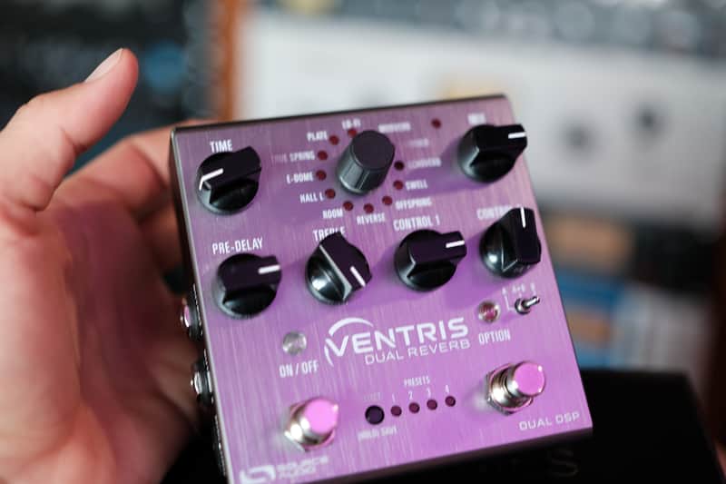 Silver and black guitar effects pedal on a black box.
