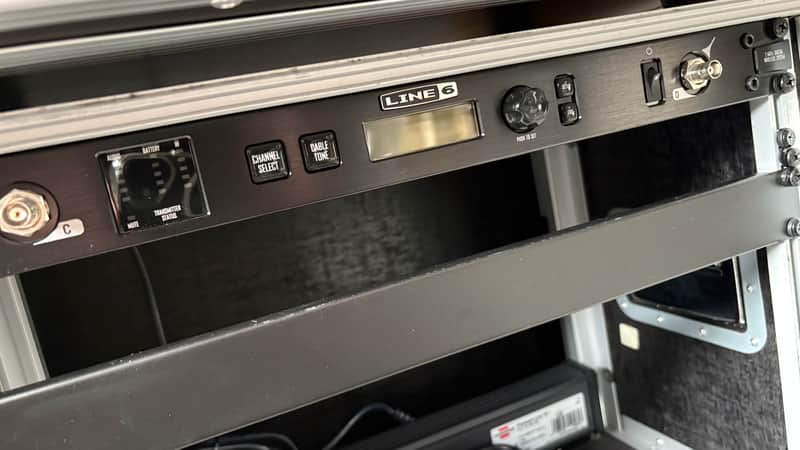 Black audio receiver on a silver equipment rack, with a small black unit on top.