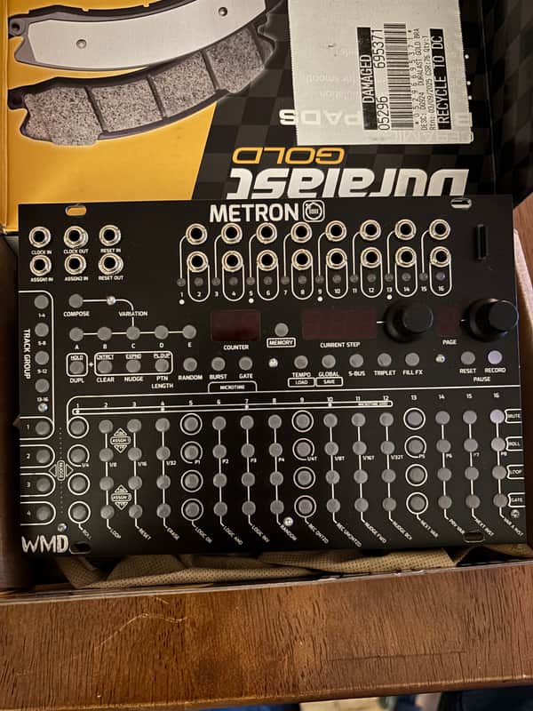 Black electronic synthesizer with white and orange knobs and buttons.