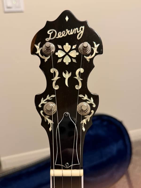 White banjo with dark rim, gold hardware, and visible tuning pegs.
