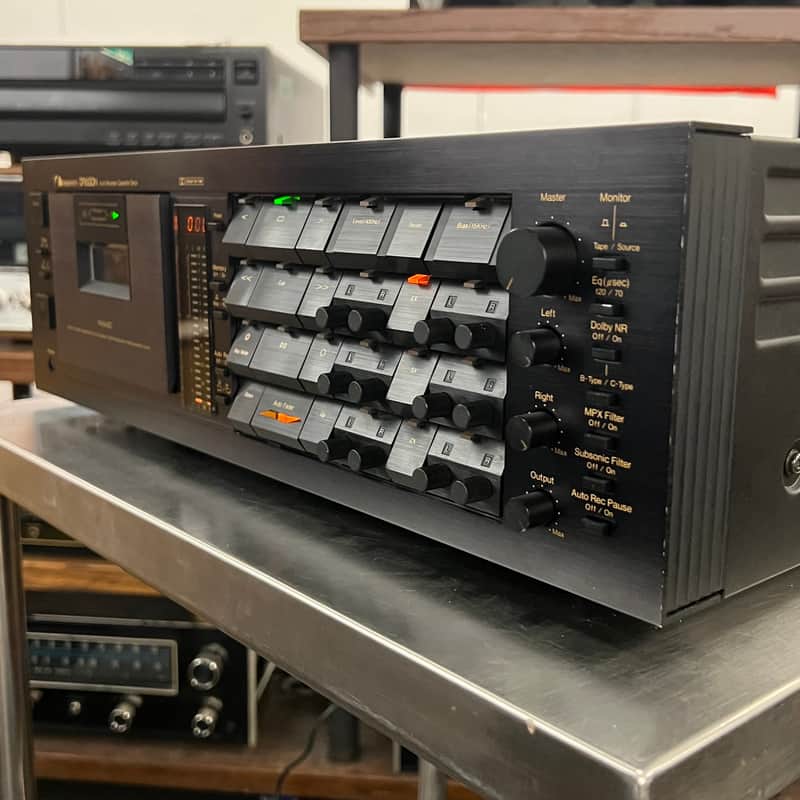 Black Nakamichi Dragon cassette deck with numerous small, colorful accessories scattered below.