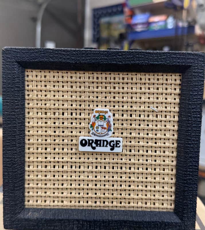 Orange woven wicker-style display case with a small central emblem.