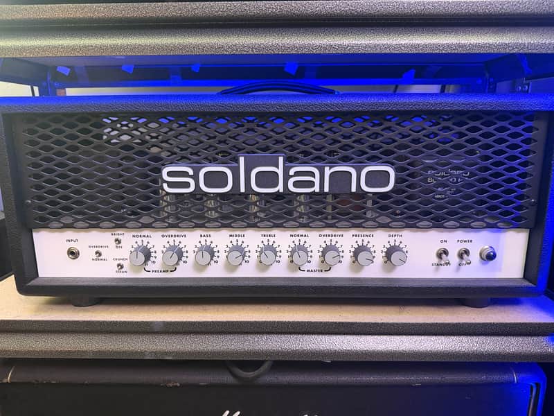 Black Soldano guitar amp with silver knobs, sitting on wooden surface.