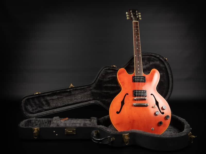 Red electric guitar with chrome hardware, shown against a dark background.