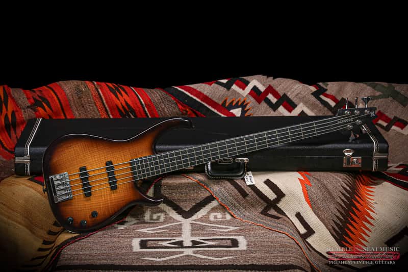 Brown wood grain electric guitar with black hardware, resting on brown couch.