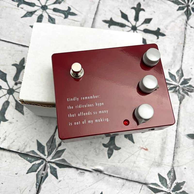 Red rectangular plaque with white text and three silver circular elements.