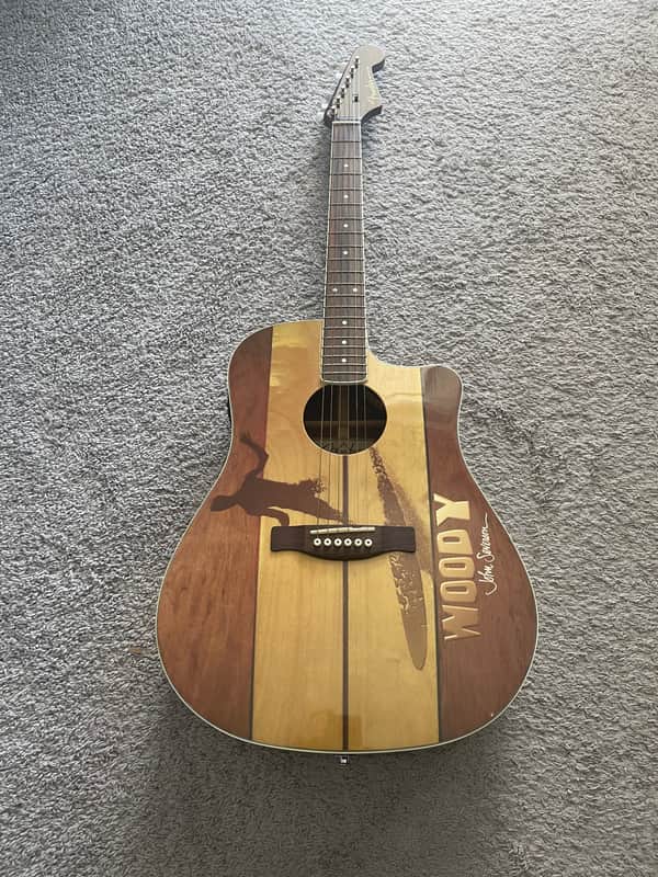 Dark brown acoustic guitar with sunburst inlay, resting on a gray surface.