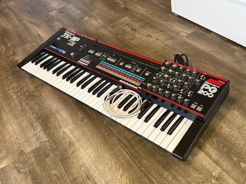 Black Roland JX-3P synthesizer keyboard with red accents, displayed on a shelf.