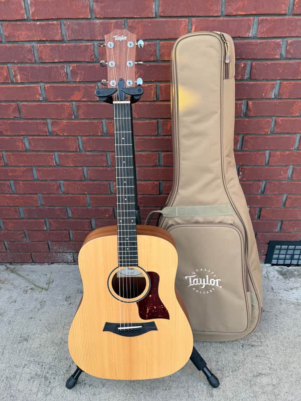 A natural wood acoustic guitar on a stand, showing its body and neck.