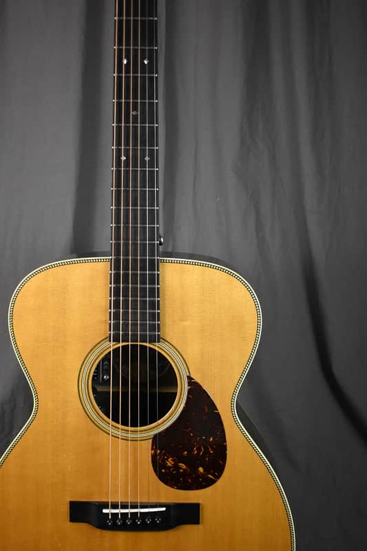 Acoustic guitar, natural wood finish, visible soundhole and pickguard.