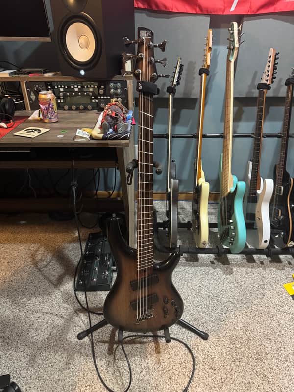 Brown electric bass guitar with wooden grain finish, resting on a wooden surface.