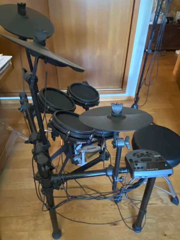 Black cymbal and drum set on stands. Hardware and drum heads visible.