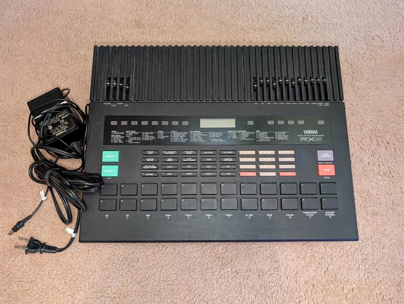 Black Yamaha RX8 digital rhythm programmer with various buttons and display.