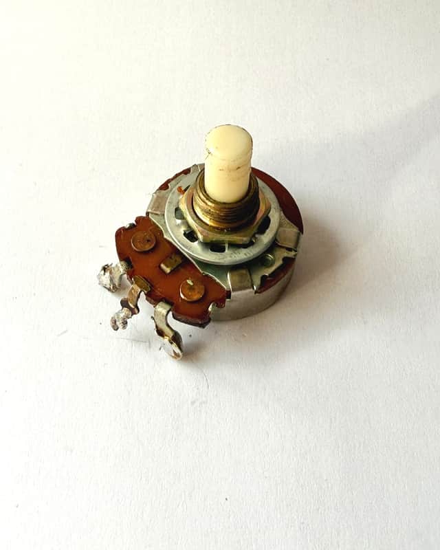 Small, silver and brown electronic component with blue cylindrical top.