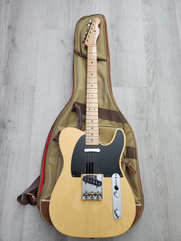 Light yellow electric guitar with black pickguard, displayed on wooden floor.