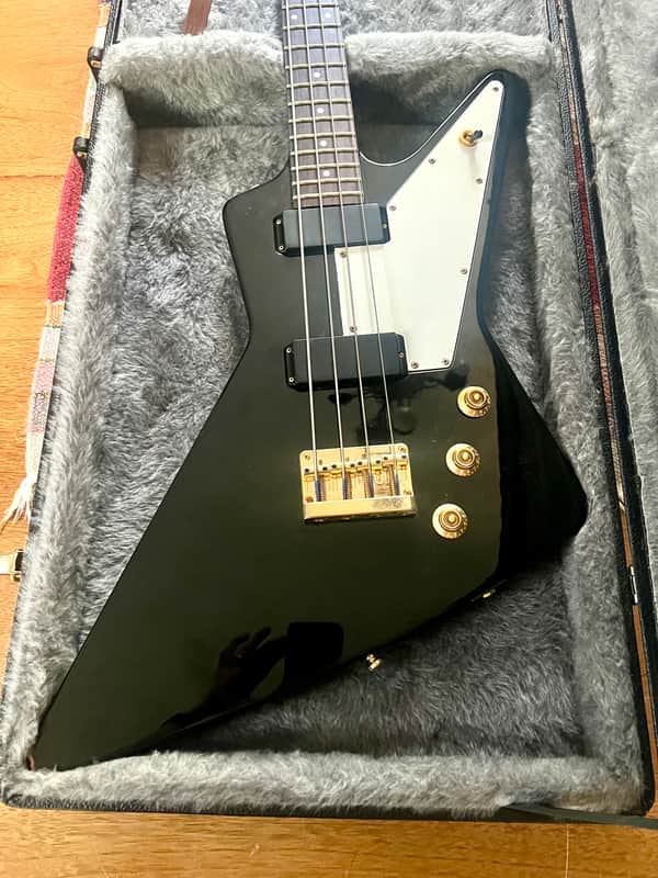 Black electric guitar in hard case, visible fretboard and pickguard.